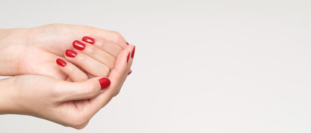 Belle main féminine peignant des ongles rouges en gel acrylique style de mode