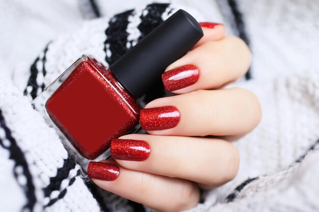 Belle main féminine avec pull manucure rouge Ambiance chaleureuse et concept festif