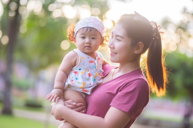 Belle maman asiatique et bébé jouant le bonheur dans le parc