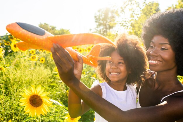 Belle maman et fille afro-américaines jouant et s'amusant dans un champ de tournesols