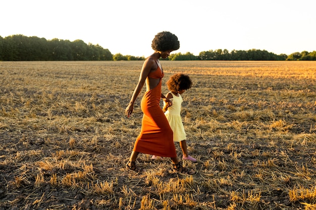 Belle maman et fille afro-américaines jouant et s'amusant dans un champ de tournesols