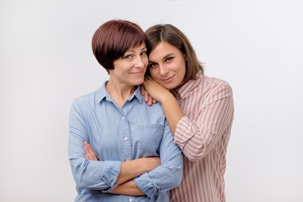 Belle maman mature et sa fille adulte se serrent dans leurs bras en regardant la caméra et en souriant