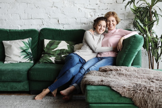 Belle maman senior et sa fille adulte se serrent dans leurs bras en regardant la caméra et souriant