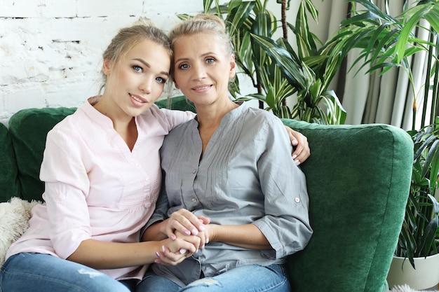 Photo belle maman senior et sa fille adulte se serrent dans leurs bras en regardant la caméra et souriant