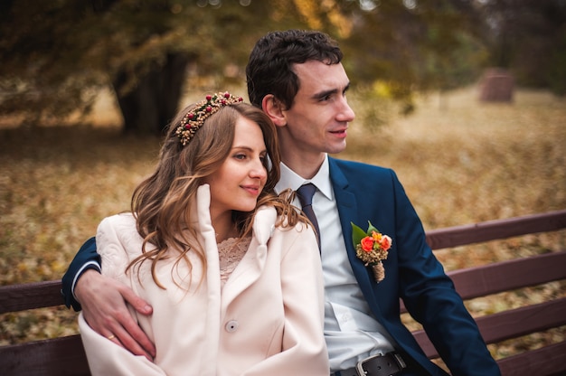 La belle mariée et beau marié assis sur un banc