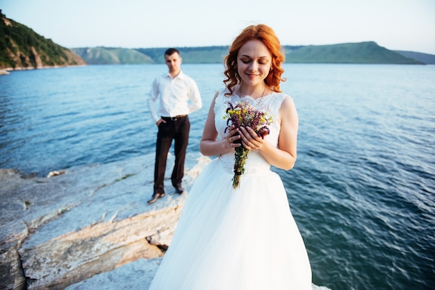 Belle mariée blonde magnifique et marié élégant sur les rochers