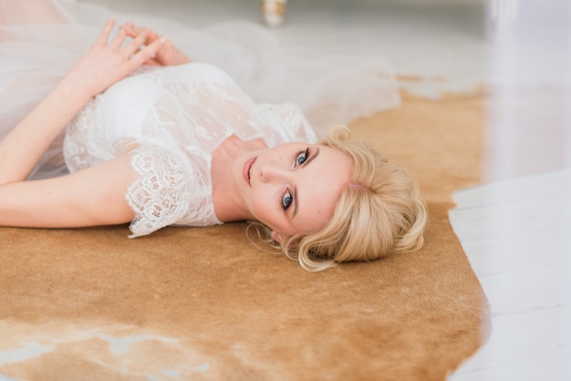 Belle mariée blonde vêtue d'une robe en voile blanc