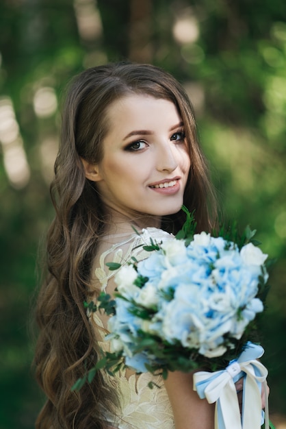 Belle mariée brune avec des boucles dans la nature