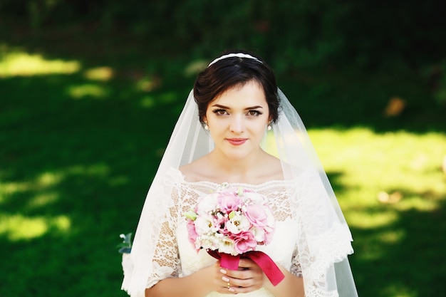 Belle mariée brune avec bouquet à l'extérieur