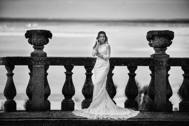 Photo belle mariée dans une robe luxueuse se dresse sur un grand balcon