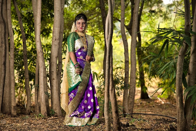 Belle mariée indienne en saree traditionnelle posant à l'extérieur du parc