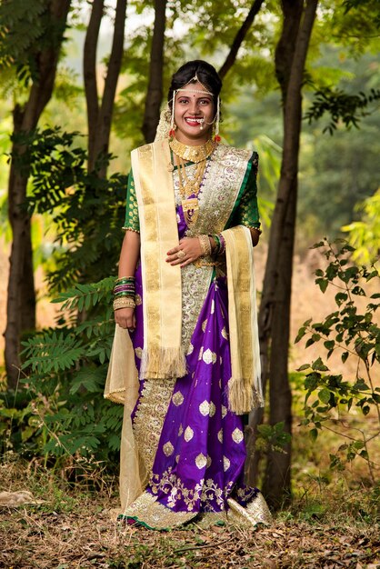 Belle mariée indienne en saree traditionnelle posant à l'extérieur du parc