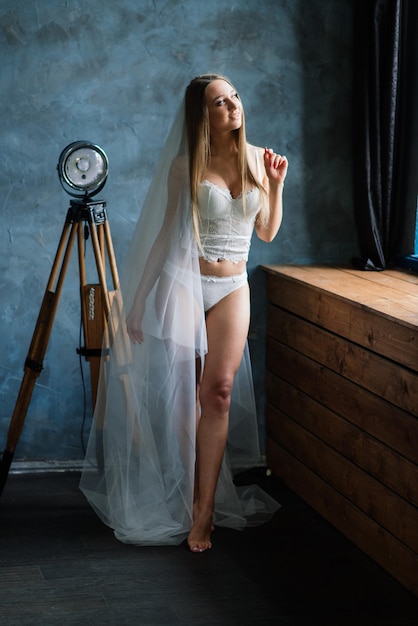 Belle mariée en lingerie blanche assise dans sa chambre et son studio.