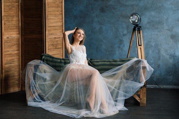 Belle mariée en lingerie blanche assise dans sa chambre et son studio.