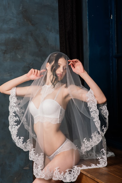 Belle mariée en lingerie blanche assise dans sa chambre et studio