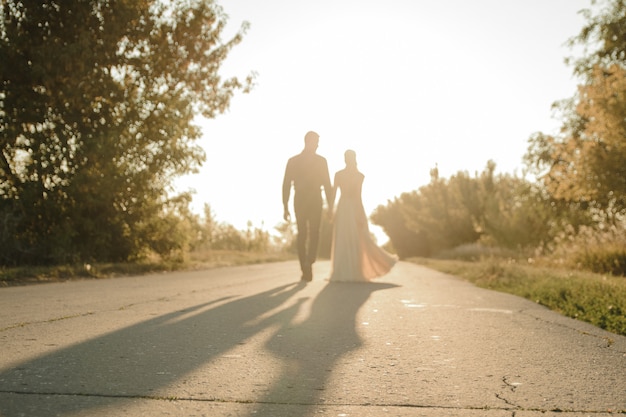 Belle mariée et le marié marchent contre le soleil. Deux amants s'embrassent et s'embrassent