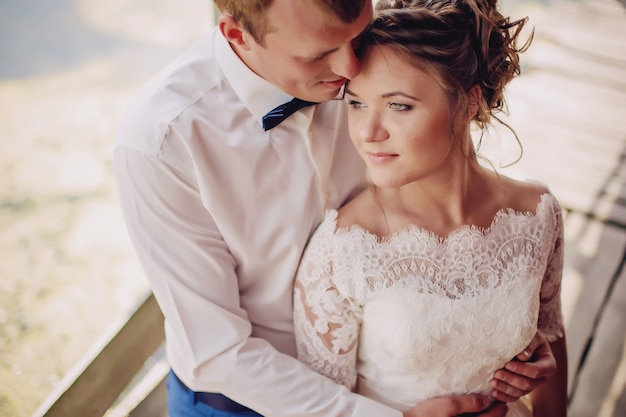 Belle mariée et le marié posant sur un pont