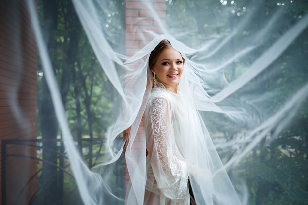 Belle mariée un matin de mariage en peignoir et voile