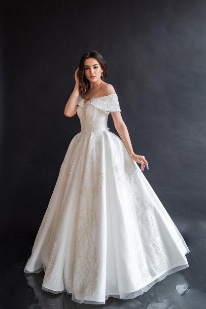 Belle mariée portant une robe de mariée dans un intérieur sombre