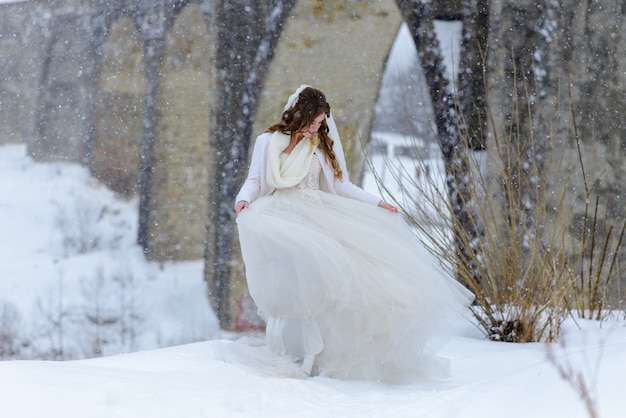 Belle mariée posant près d'un vieux pont aqueduc abandonné. La mariée admire sa robe