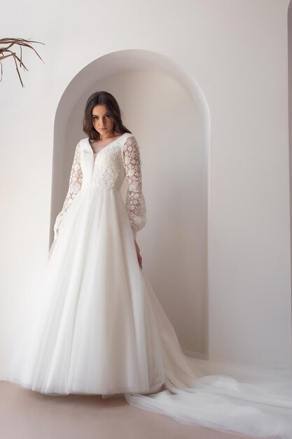 Belle mariée posant en robe de mariée dans un studio photo blanc