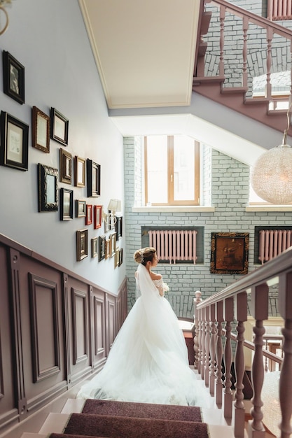 Une belle mariée en robe blanche descend les escaliers