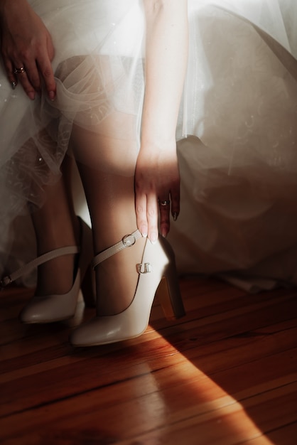 Belle mariée en robe blanche met des chaussures sur ses pieds