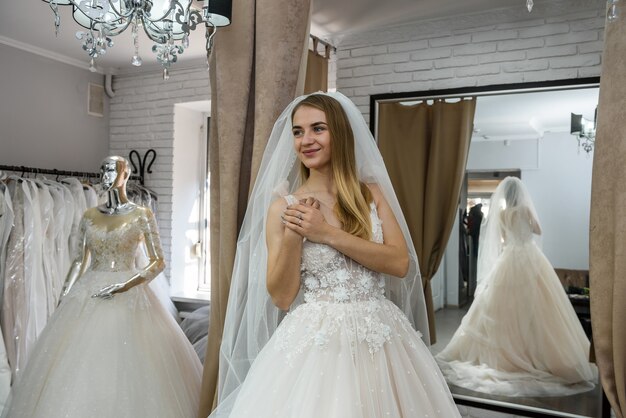 Belle mariée en robe de mariée debout dans la boutique