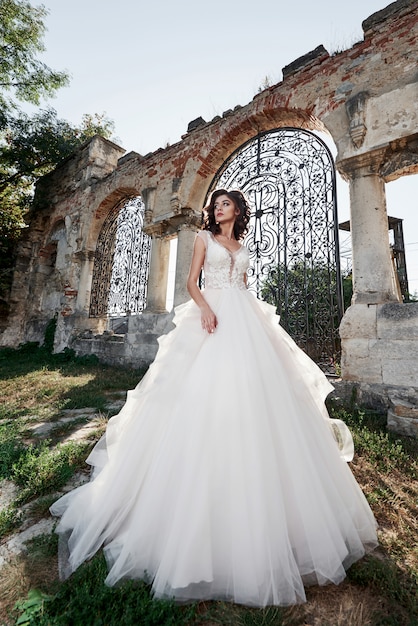 Belle mariée en robe de mariée, photographiée le jour du mariage près du vieux château.