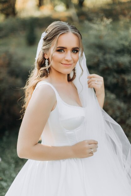 Une belle mariée se dresse sur la nature dans la verdure