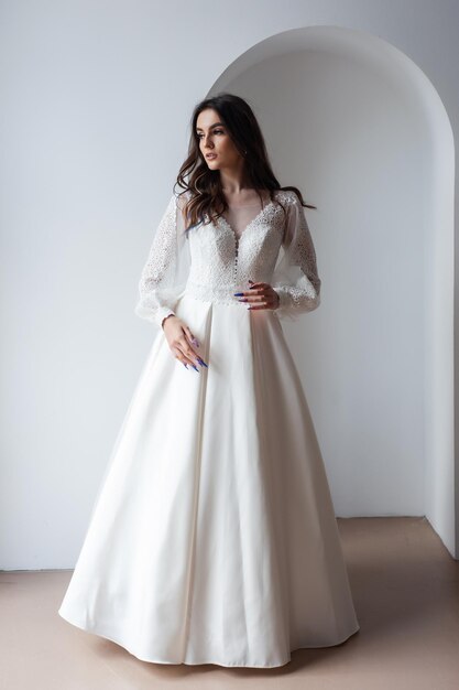 Belle mariée séduisante en robe de mariée avec fond blanc longue jupe pleine