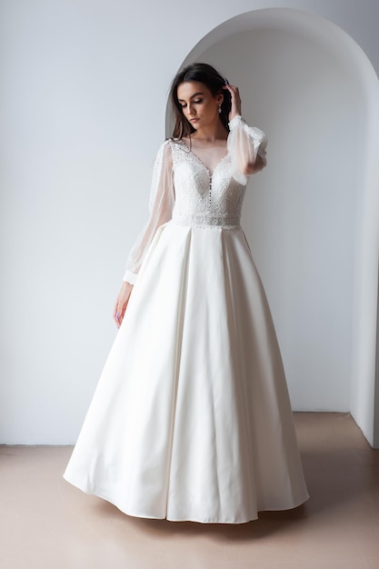 Belle mariée séduisante en robe de mariée avec fond blanc longue jupe pleine