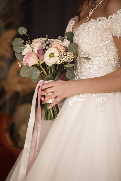 Belle mariée tenant un délicat bouquet de fleurs dans ses mains le jour du mariage