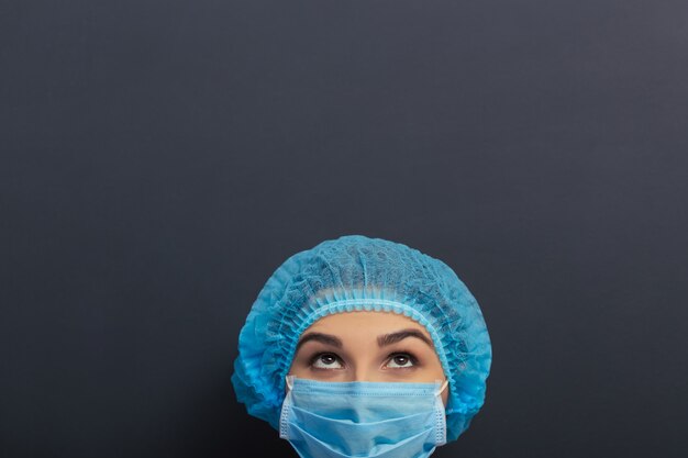 Belle médecin en blouse médicale blanche, cap et masque.