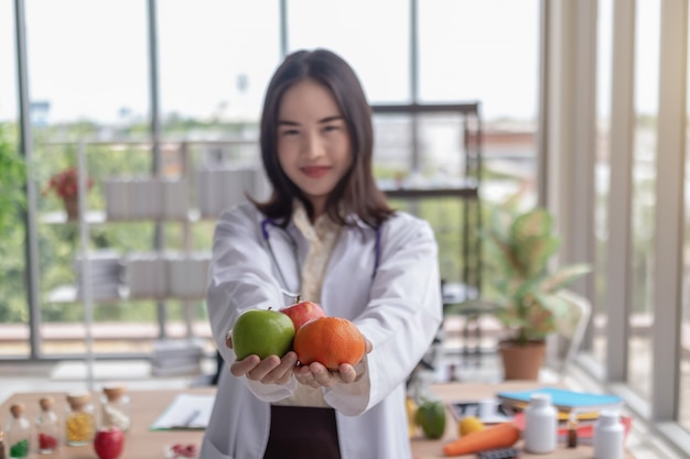 Belle médecin montre des fruits dans le bureau.