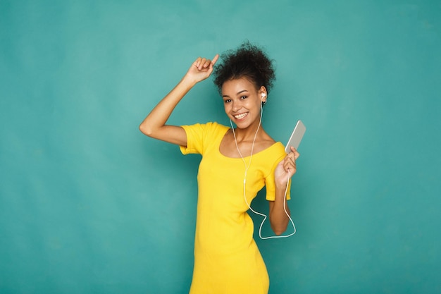 Belle mélodie. Femme écouter de la musique dans des écouteurs, debout sur fond de studio bleu, espace pour copie