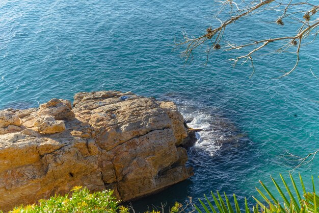 Photo belle mer bleue en journée ensoleillée avec rock