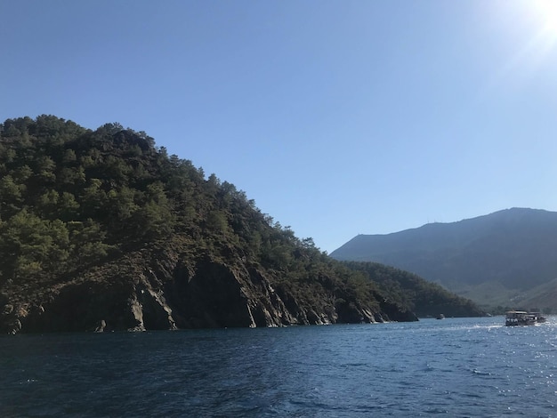 Belle mer bleue et petits navires sur fond de hautes montagnes dans un cadre touristique chaleureux