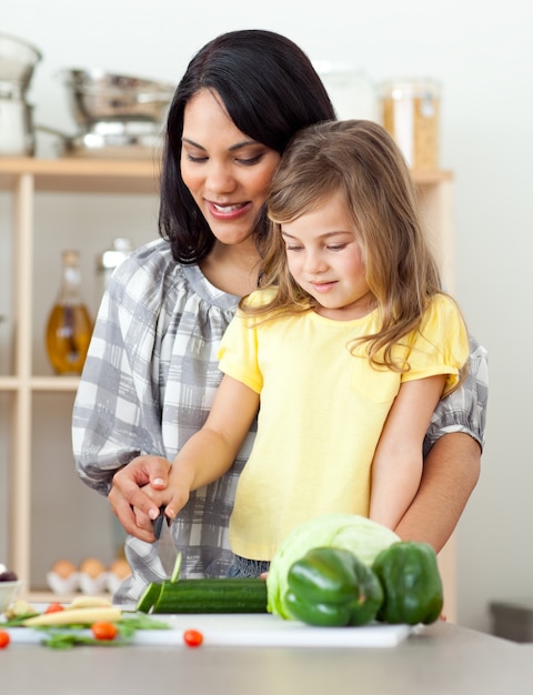 Belle mère aidant sa fille à couper les légumes