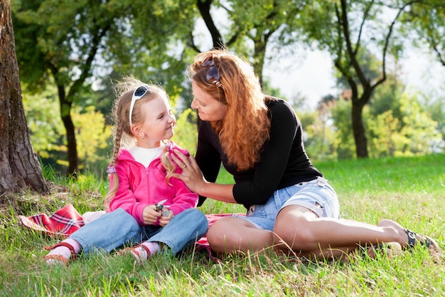 Belle mère aimante et petite fille se reposant dans le parc