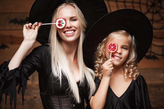 belle mère caucasienne et sa fille en costumes de sorcière célébrant Halloween avec des bonbons Halloween
