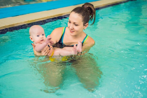 Belle mère enseignant à une jolie petite fille comment nager dans une piscine Enfant s'amusant dans l'eau avec maman