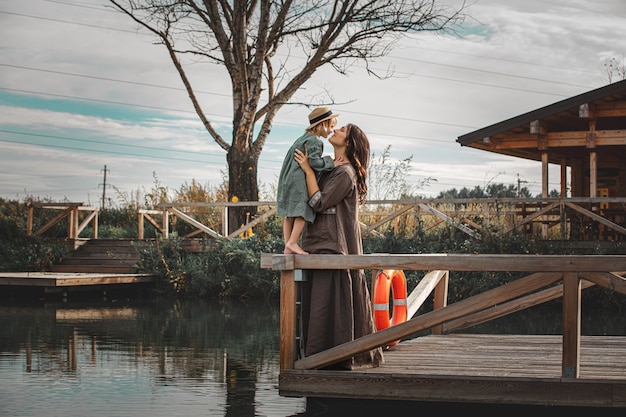 Belle mère et fille de famille heureuse ensemble sur une jetée en bois au bord du lac