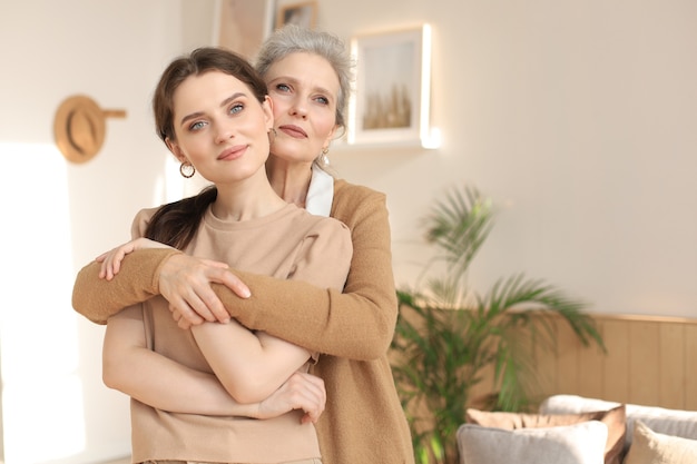 Belle mère et fille. Une jeune femme joyeuse embrasse sa mère d'âge moyen dans le salon. Portrait de famille.