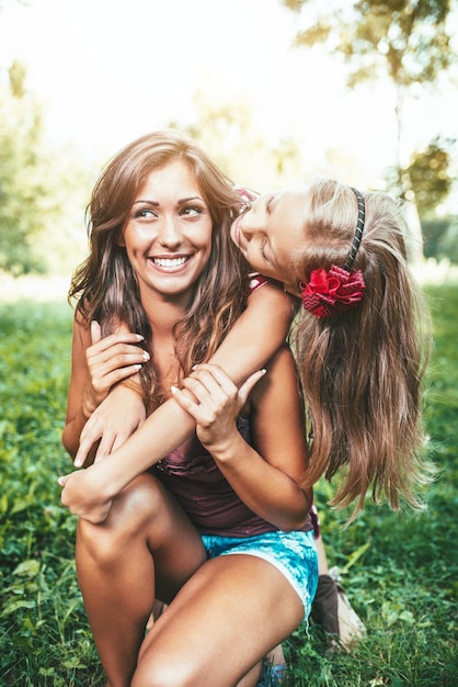 Belle mère et fille s'amusant au parc au printemps, s'embrassant et s'embrassant.