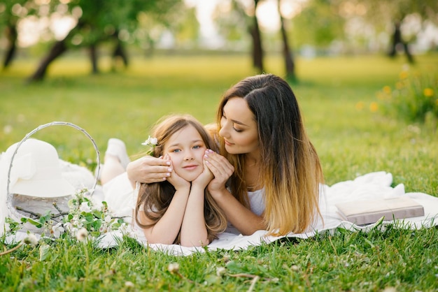 Une belle mère et sa fille sont allongées sur la plage et se détendent au grand air