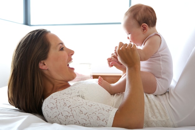 Belle mère souriante avec bébé au lit