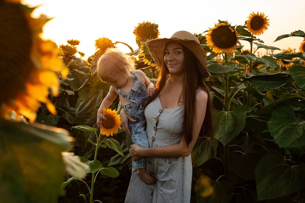 Belle mère tient un bébé dans un champ de tournesol. tendresse, sourires, bonheur.