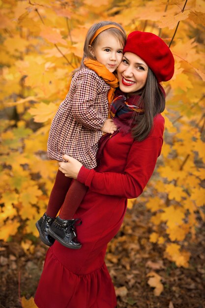 Une belle mère tient sa petite fille dans ses bras un jour d'automne