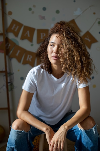 Belle métisse bouclée posant sur le fond de l'inscription joyeux anniversaire